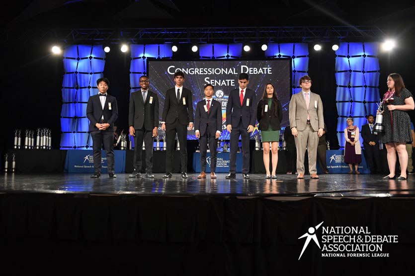 Group of students on the National Tournament stage with their trophies.